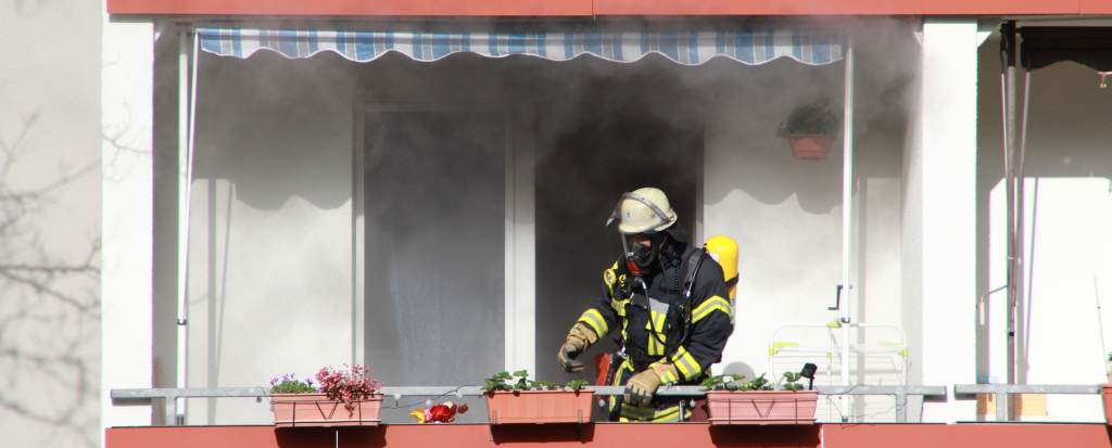 Tűzoltó egy füstölő lakás erkélyén